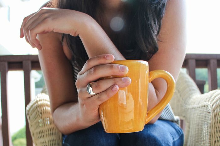 Uma mulher jovem segurando uma xícara  de café.