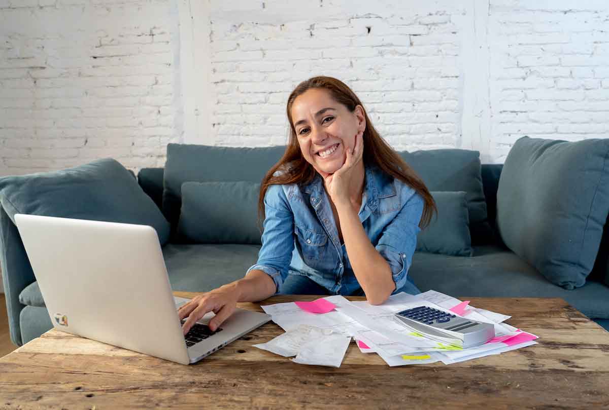 Mulher feliz enquanto empreende pela internet usando um notebook.