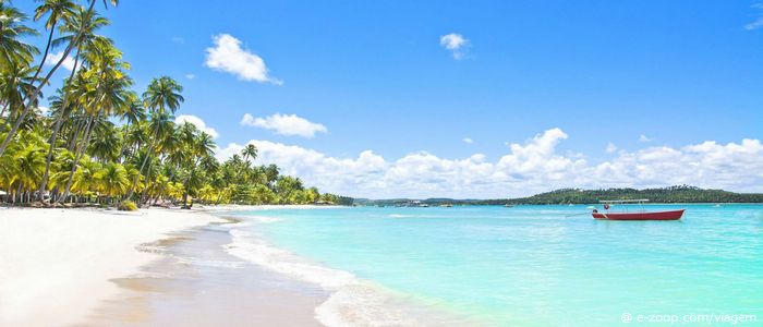 Roteiro de viagem em Salvador: Uma canoa repousa sobre as águas verdes e cristalinas de uma praia em Salvador.