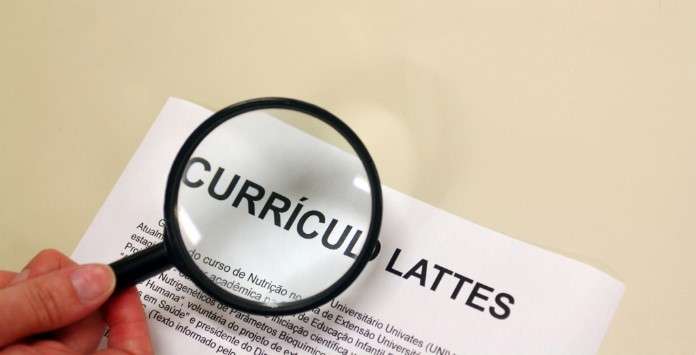 Alguém segurando uma lupa sobre um documento onde se pode ler as palavras 'Curriculun Lattes' ilustra nosso artigo sobre: Plataforma Lattes.